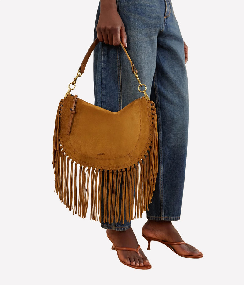 Isabel Marant Oskan Cognac suede tassel bag carried by hand with blue jeans and brown sandals