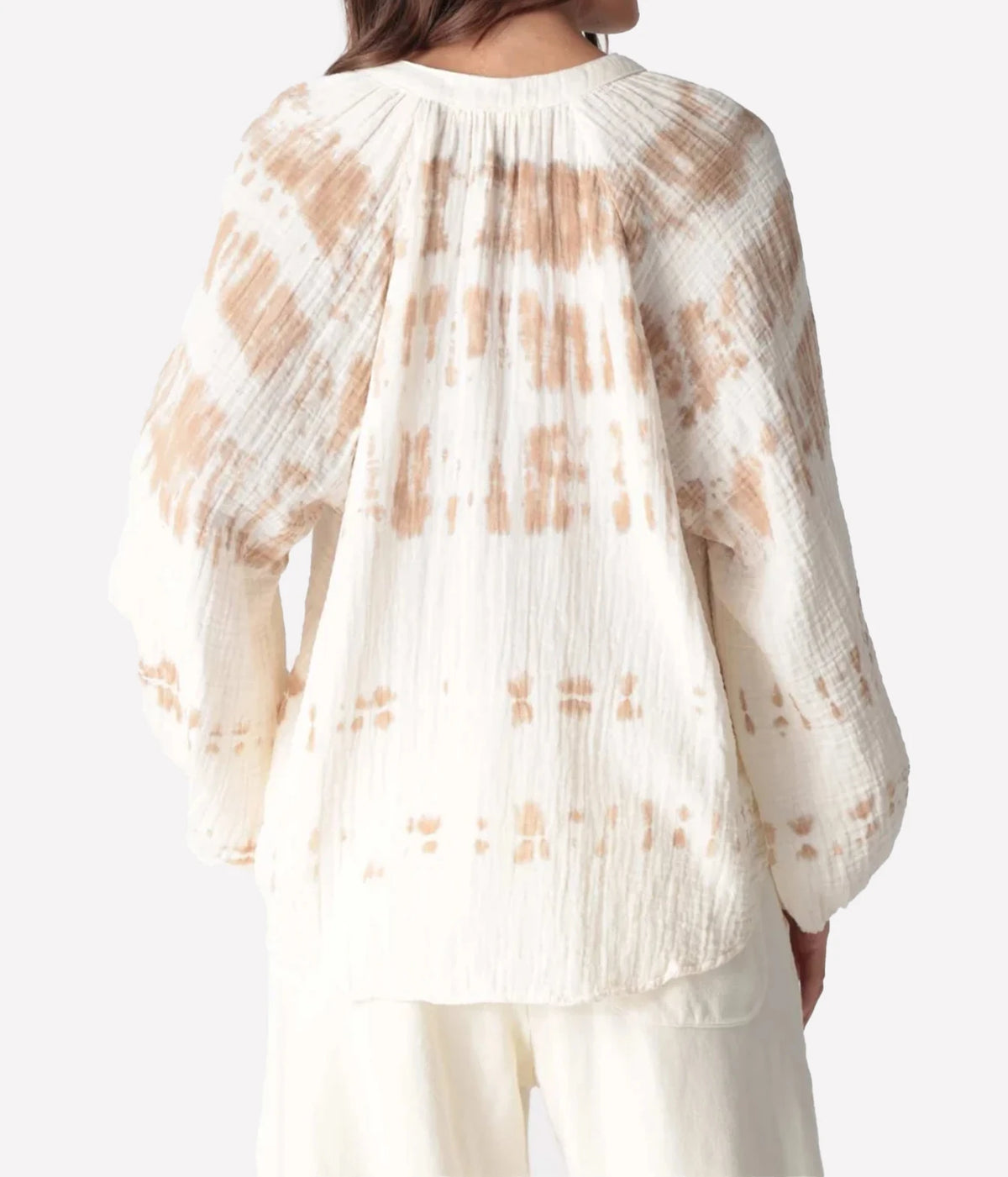 Back view of a model wearing the Electric Rose Winnie Horizon Shirt in Dune Ivory, showing the gathered yoke and tie-dye detail across the back and sleeves, with ivory trousers