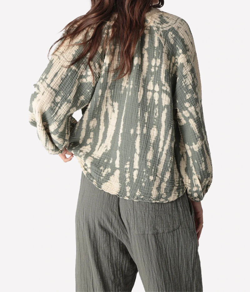 Back view of a model wearing the Electric Rose Winnie Horizon Shirt in Moss Ivory, showing the tie-dye pattern across the back and balloon sleeves, with moss green crinkle-textured pants