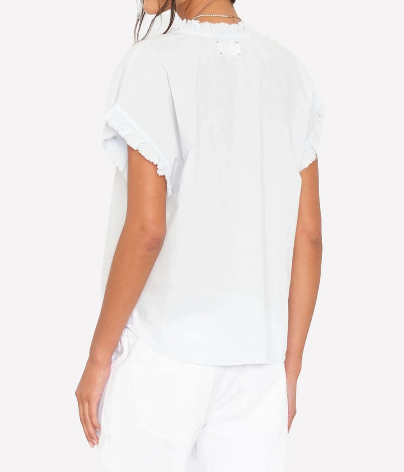 Back view of a model wearing the Xirena Darcy Top in Skylight with white jeans, showing the relaxed fit and ruffle-trimmed flutter sleeves