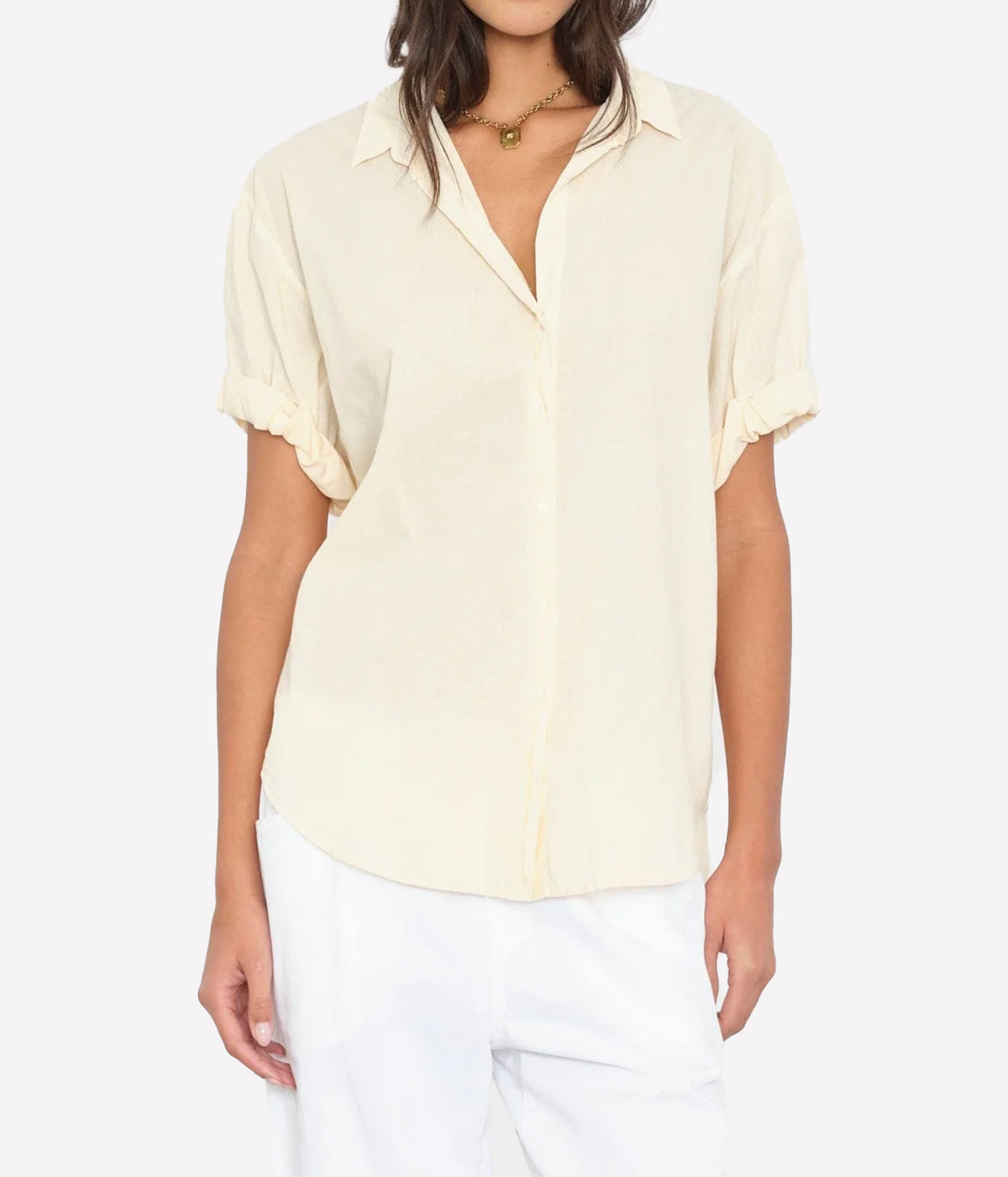 Model wearing the Xirena Channing Shirt in Oysterette half-tucked into white pants with a gold pendant necklace, showing the relaxed fit and rolled sleeves